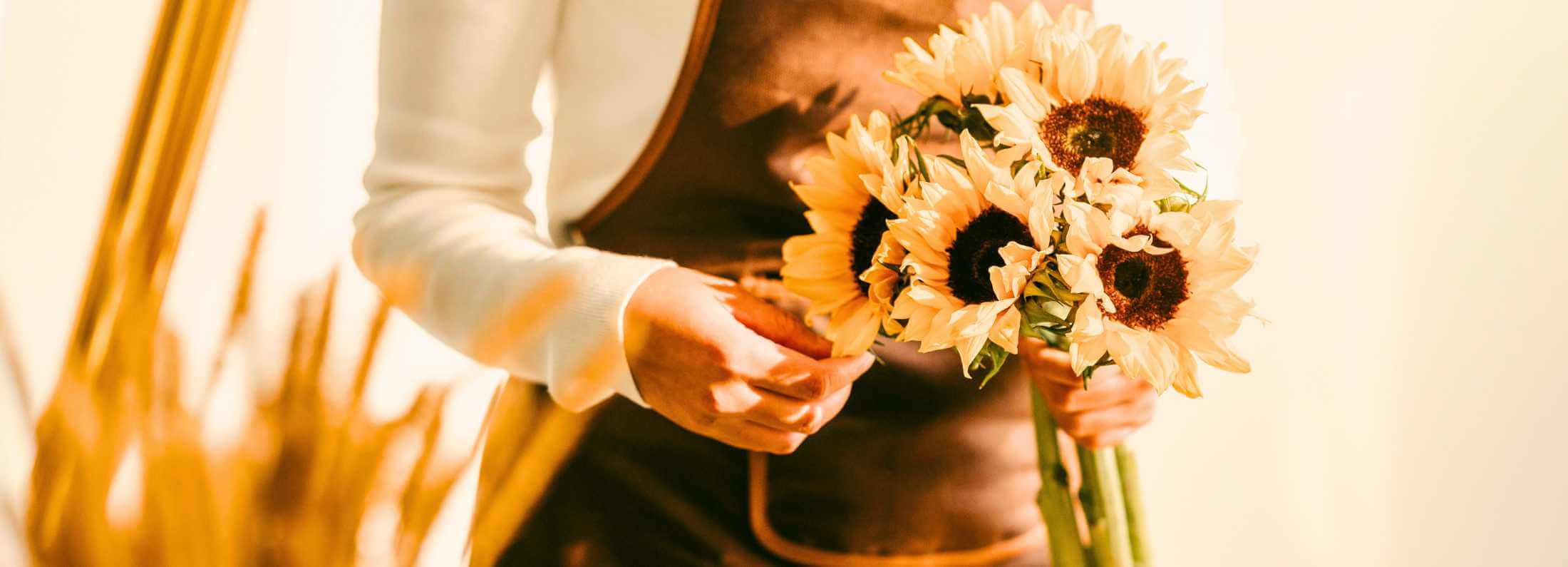 Women holding a bouqet with fresh sunflowers